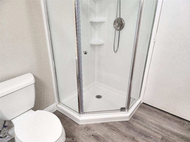 bathroom featuring hardwood / wood-style flooring, toilet, and a shower with shower door