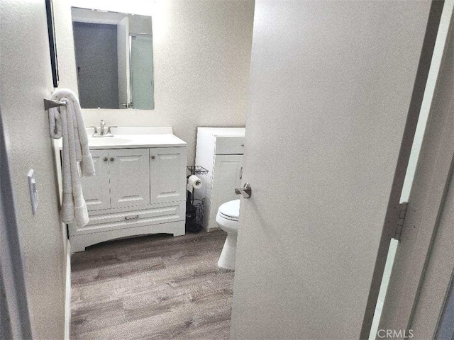 bathroom with vanity, hardwood / wood-style flooring, and toilet