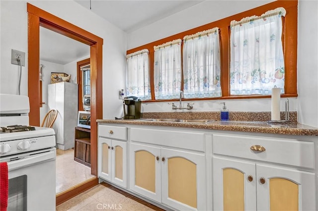 kitchen with white cabinetry, sink, and gas range gas stove