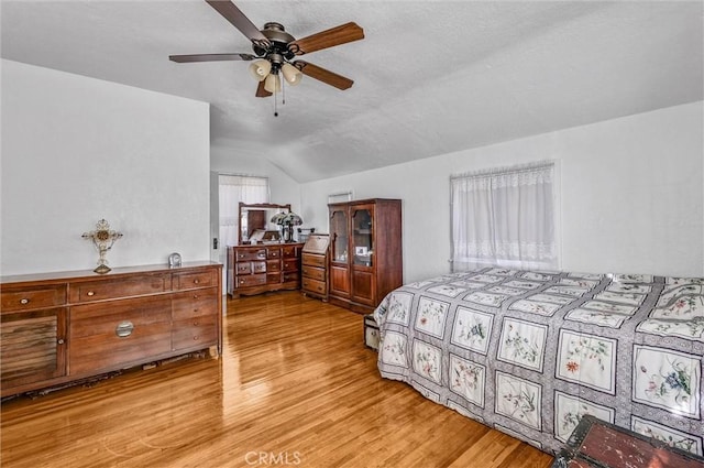 bedroom with ceiling fan, lofted ceiling, and light wood-type flooring