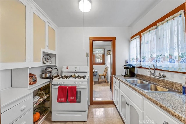 kitchen featuring white range with gas cooktop, sink, and white cabinetry