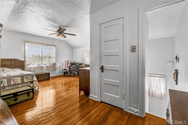 bedroom with ceiling fan, vaulted ceiling, dark hardwood / wood-style floors, and a textured ceiling