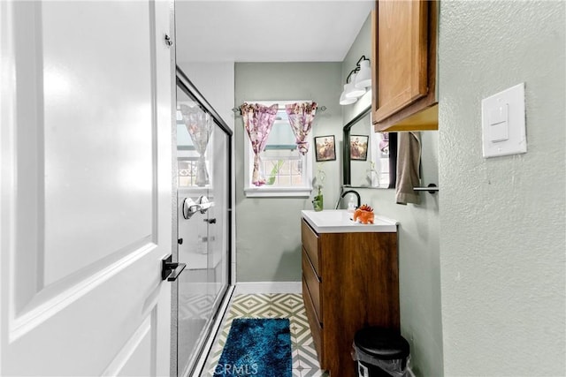 full bath featuring a stall shower, tile patterned floors, baseboards, and vanity