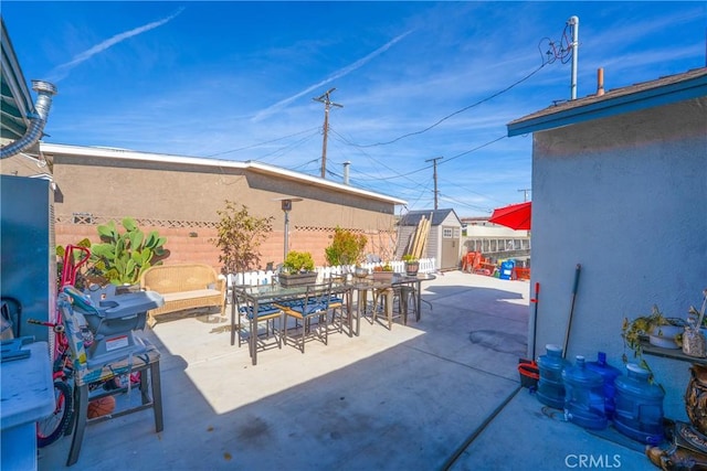 view of patio / terrace with a shed, an outdoor structure, a fenced backyard, and outdoor dining space