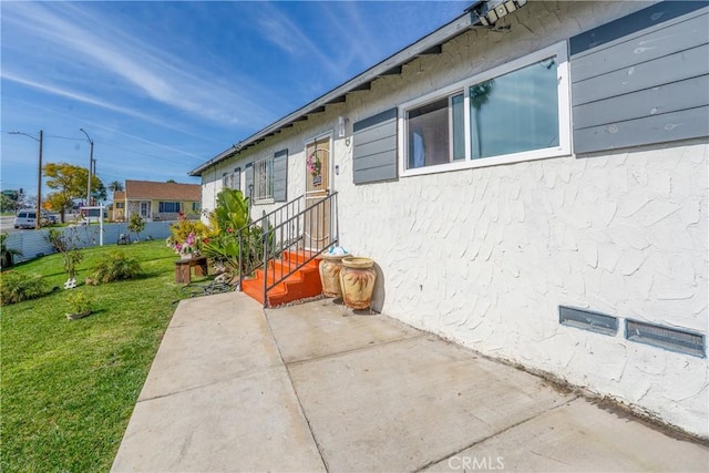 exterior space featuring a yard, a patio area, and stucco siding