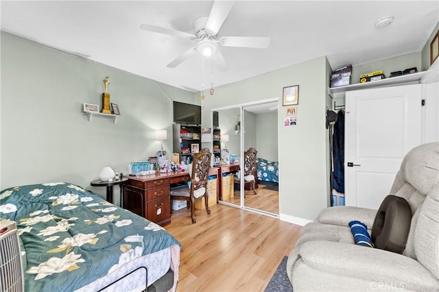 bedroom featuring light wood-type flooring, baseboards, a ceiling fan, and a closet