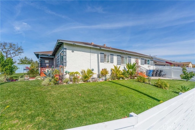 view of front of house featuring fence private yard, a front lawn, and stucco siding