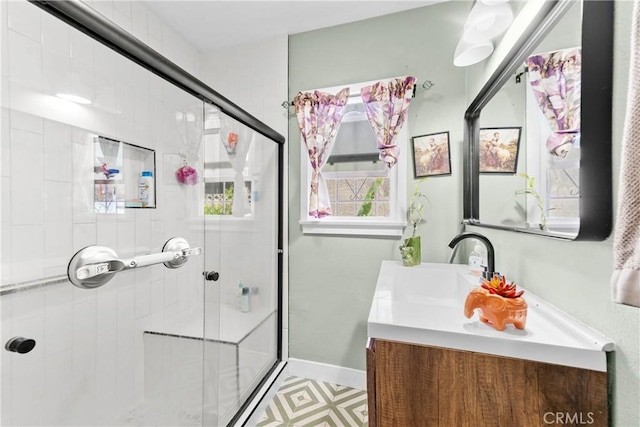 full bathroom with a tile shower, vanity, and baseboards