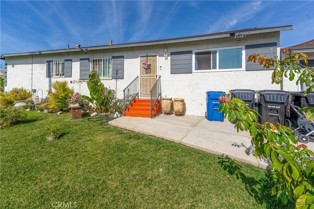 view of front of house featuring stucco siding, a patio, and a front yard