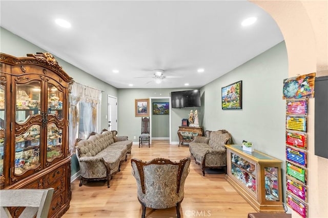 living room featuring light wood-type flooring, arched walkways, a ceiling fan, and recessed lighting