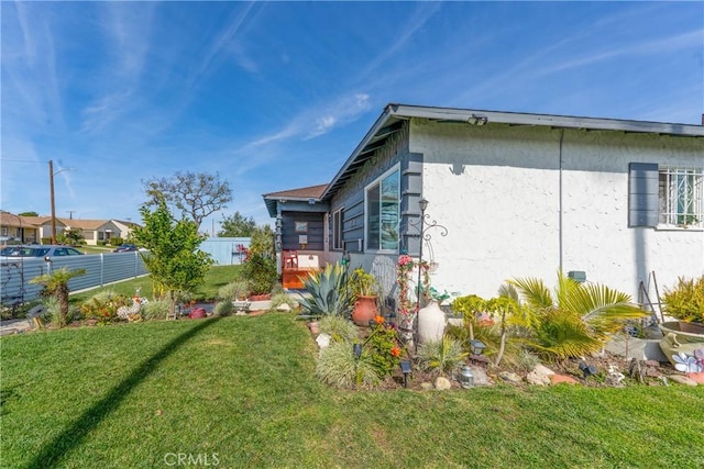 view of home's exterior featuring a lawn and fence