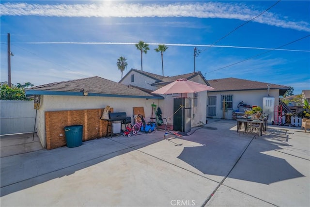 rear view of property with a patio area, fence, and stucco siding