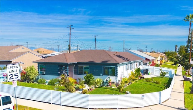 view of front facade with a residential view, fence, and a front lawn