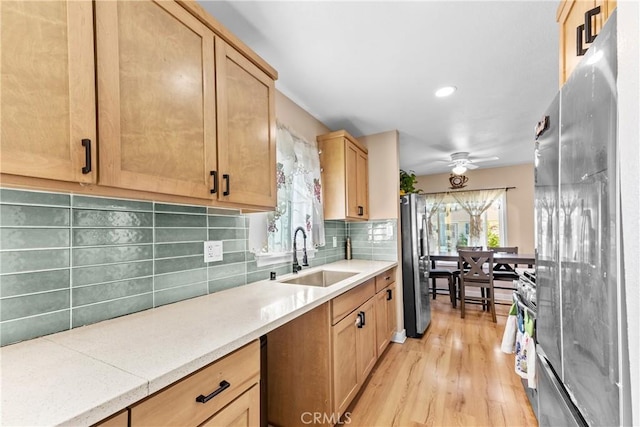 kitchen with a sink, backsplash, freestanding refrigerator, plenty of natural light, and stainless steel fridge