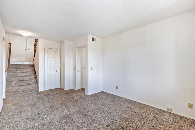 carpeted spare room featuring a textured ceiling