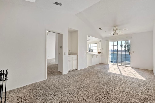 unfurnished living room featuring vaulted ceiling, sink, light colored carpet, and ceiling fan