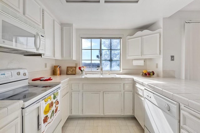 kitchen with white cabinetry, sink, tile countertops, and white appliances