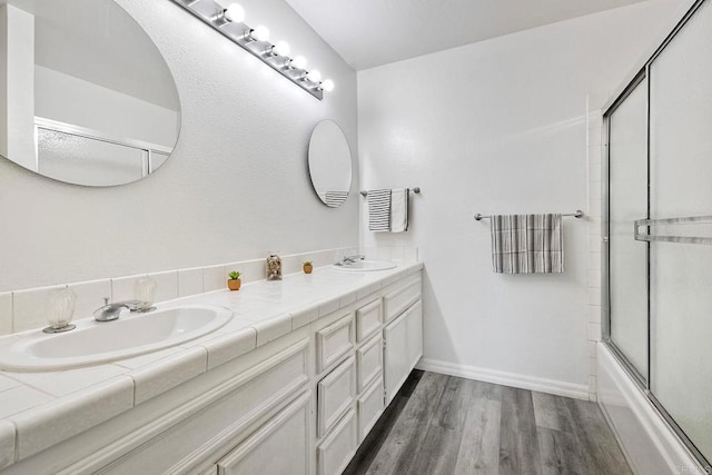 bathroom featuring vanity, hardwood / wood-style floors, and combined bath / shower with glass door