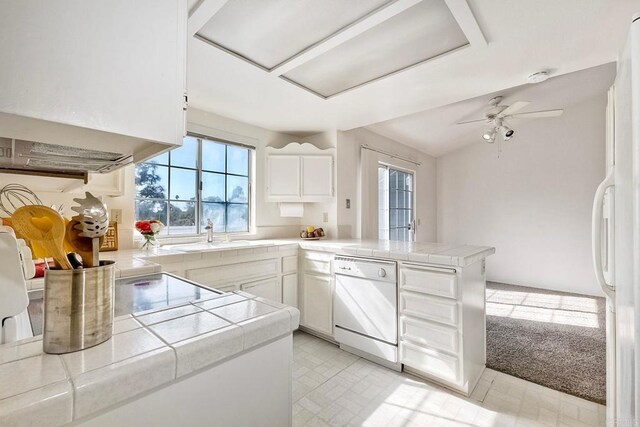 kitchen with white appliances, tile counters, kitchen peninsula, and white cabinets