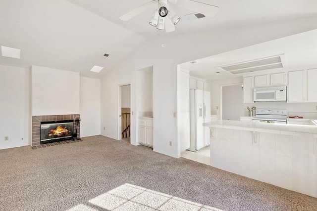 unfurnished living room featuring a brick fireplace, vaulted ceiling, light colored carpet, and ceiling fan