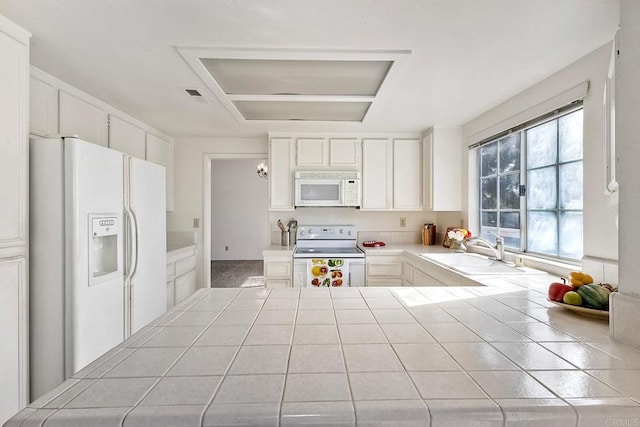 kitchen with sink, tile countertops, white cabinets, and white appliances