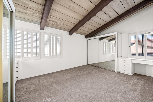 unfurnished bedroom with vaulted ceiling with beams, built in desk, light carpet, wooden ceiling, and a closet