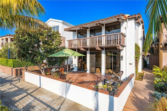 view of front of property featuring a balcony and a patio area