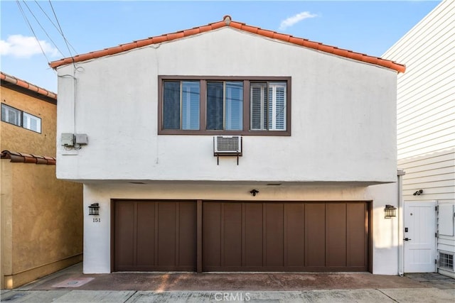 view of property exterior with a garage and an AC wall unit