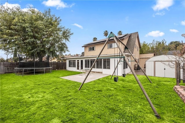 rear view of house with a shed, a trampoline, a patio area, and a lawn