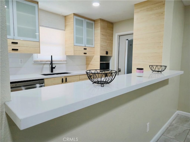 kitchen featuring sink, a kitchen breakfast bar, decorative backsplash, stainless steel dishwasher, and kitchen peninsula