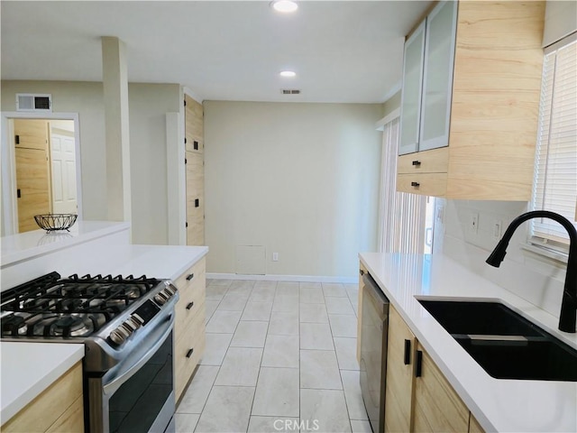 kitchen with stainless steel appliances, sink, light brown cabinets, and light tile patterned floors