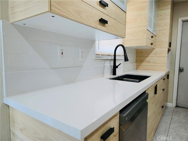 kitchen with sink, light brown cabinets, black dishwasher, and light tile patterned flooring