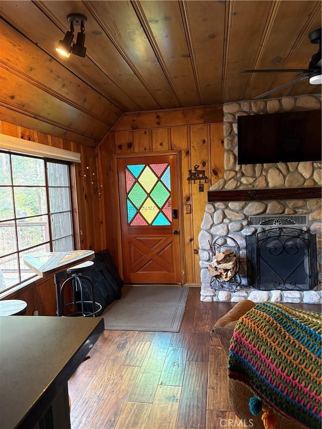 foyer featuring wood walls, wood-type flooring, vaulted ceiling, wooden ceiling, and ceiling fan