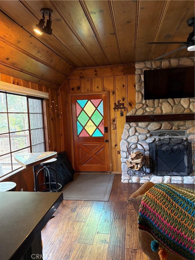 foyer featuring wooden walls, vaulted ceiling, wooden ceiling, a fireplace, and hardwood / wood-style flooring