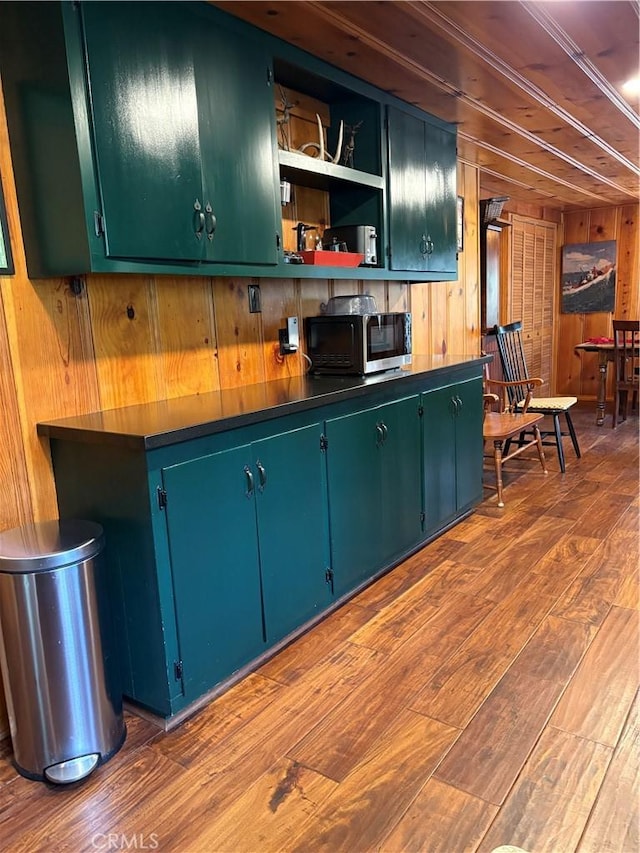 kitchen with stainless steel microwave, wood walls, open shelves, and dark wood-style flooring