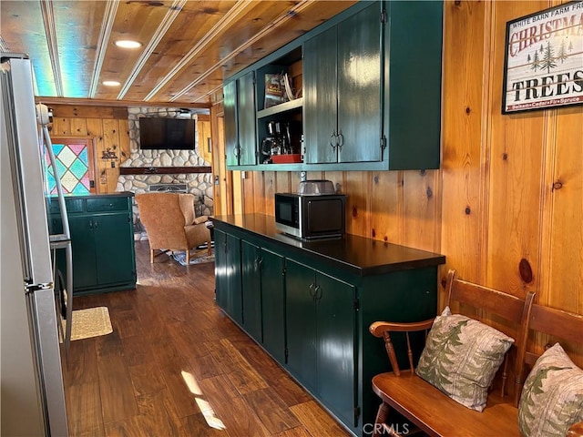 interior space with wood walls, open shelves, freestanding refrigerator, and green cabinetry