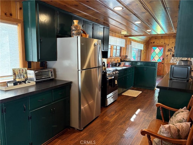 kitchen featuring wooden walls, dark wood-style floors, appliances with stainless steel finishes, dark countertops, and wooden ceiling