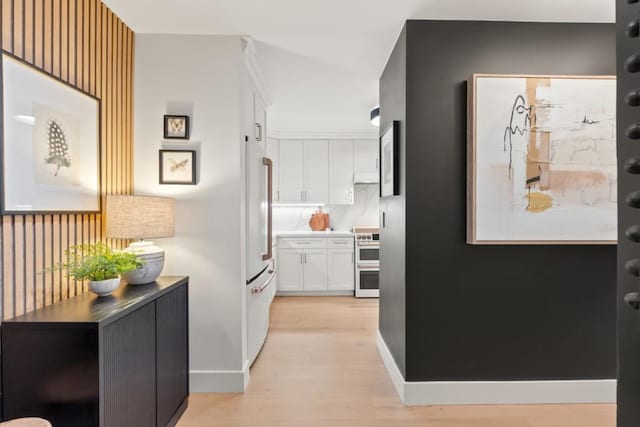 kitchen with high end white refrigerator, double oven range, light wood-type flooring, and white cabinets