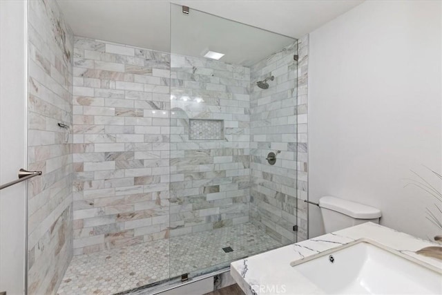 bathroom featuring toilet, sink, and a tile shower