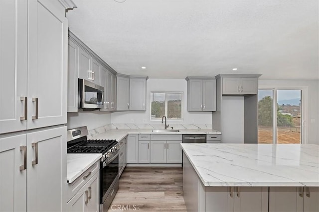 kitchen featuring sink, gray cabinets, light stone countertops, and appliances with stainless steel finishes