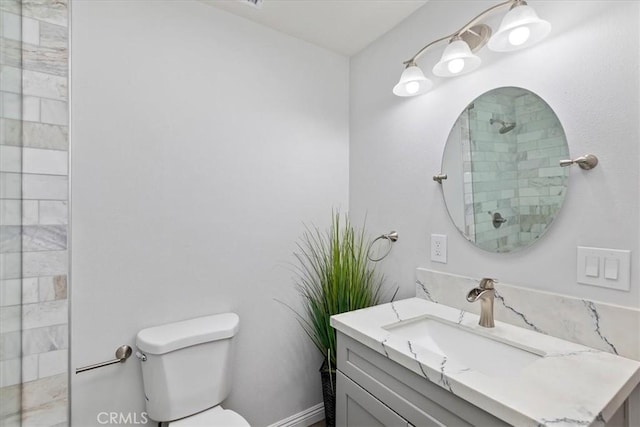 bathroom featuring vanity, tiled shower, and toilet