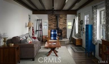 living room with beamed ceiling, a wood stove, and hardwood / wood-style floors