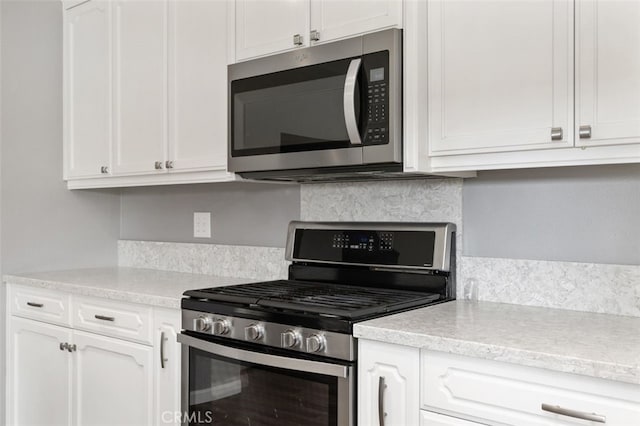 kitchen with decorative backsplash, stainless steel appliances, and white cabinets