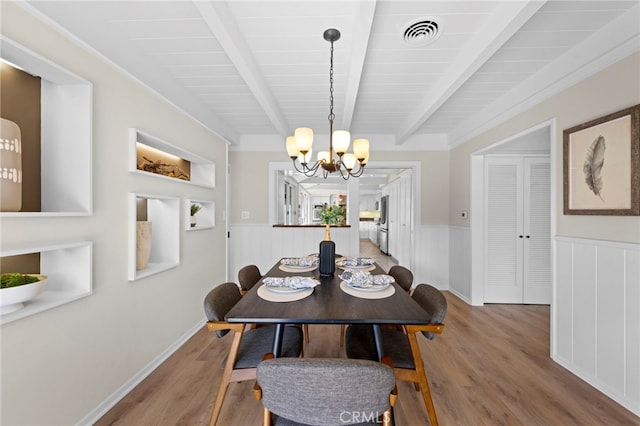 dining room featuring wood-type flooring, beam ceiling, and a notable chandelier