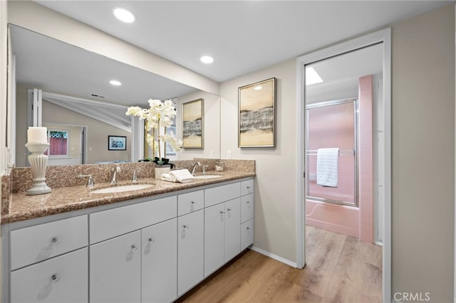 bathroom with vanity, hardwood / wood-style flooring, lofted ceiling, and enclosed tub / shower combo