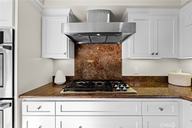 kitchen featuring white cabinets, stainless steel appliances, dark stone counters, and wall chimney exhaust hood