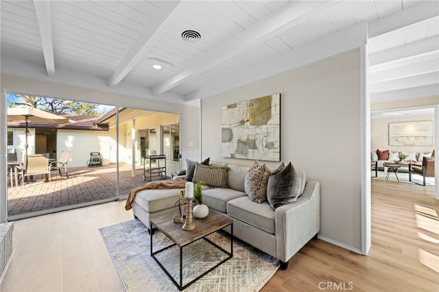 living room featuring beamed ceiling and light wood-type flooring