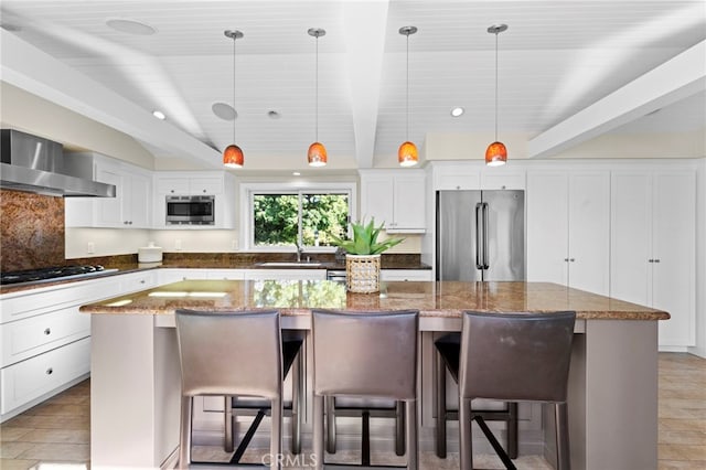 kitchen featuring decorative light fixtures, a kitchen island, a kitchen breakfast bar, and appliances with stainless steel finishes