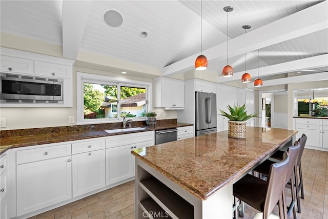 kitchen with sink, appliances with stainless steel finishes, a center island, white cabinets, and dark stone counters