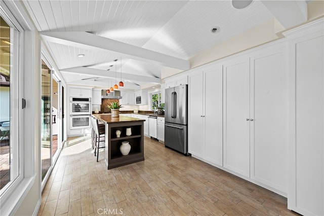 kitchen with vaulted ceiling with beams, white cabinetry, a kitchen island, pendant lighting, and stainless steel appliances